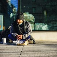 Une personne sans abris est assise sur le trottoir