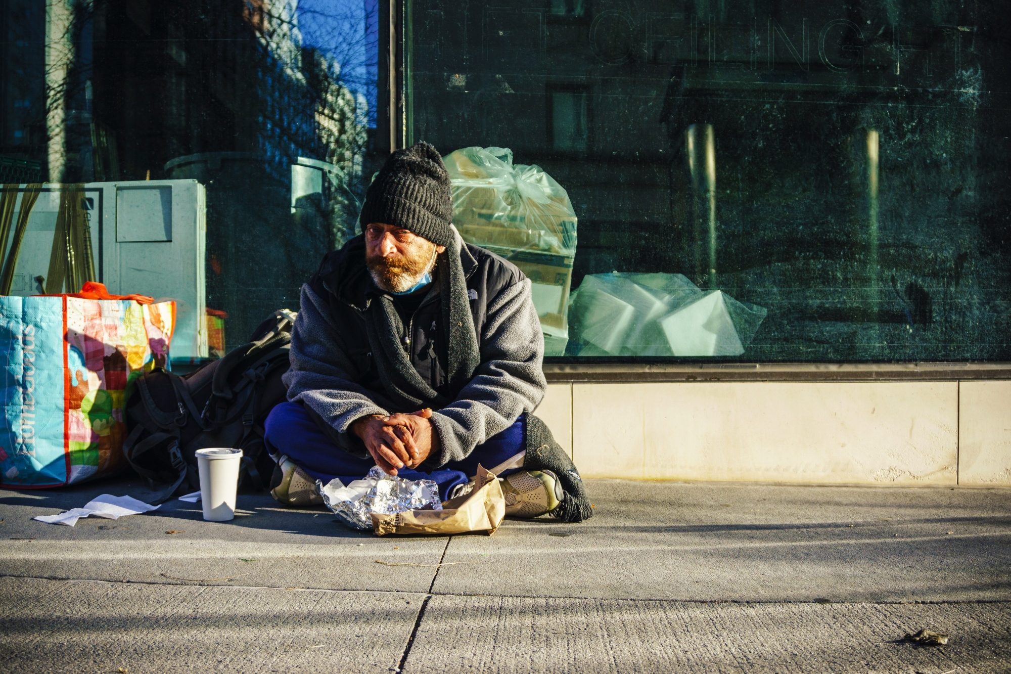 Une personne sans abris est assise sur le trottoir